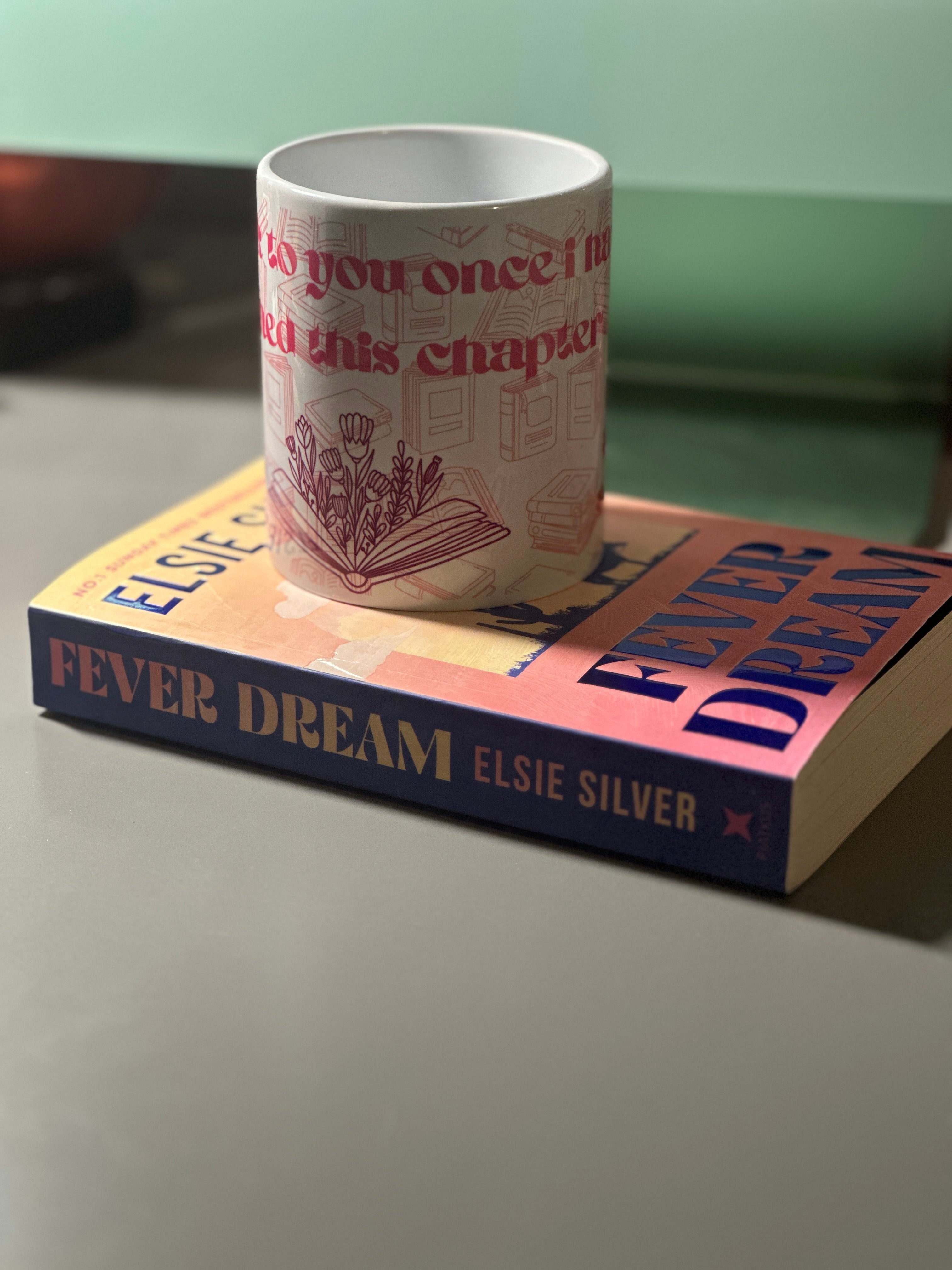 Front view of the I'll Speak To You Once I've Finished This Chapter mug on a book, showing tulip illustration