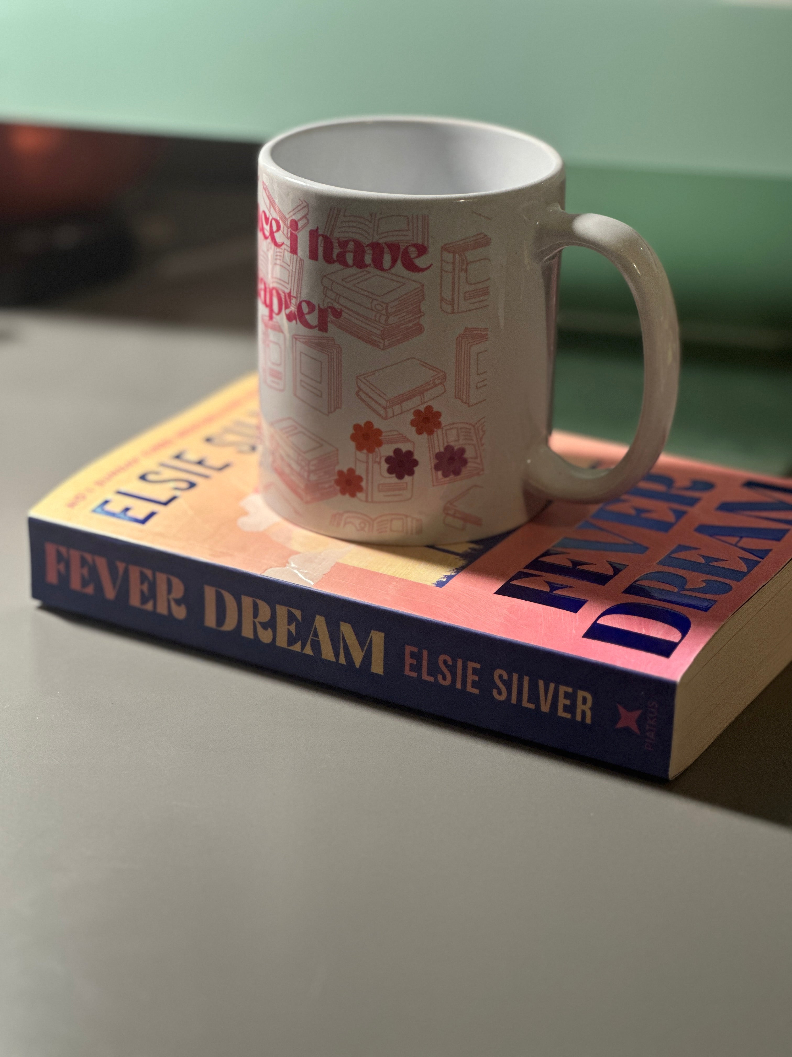 Side view of the bookish mug showing floral daisy details and chapter quote on white ceramic