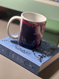 Dark fantasy mug with bats and gothic castle print resting on a witchcraft book, showing dramatic purple and red design